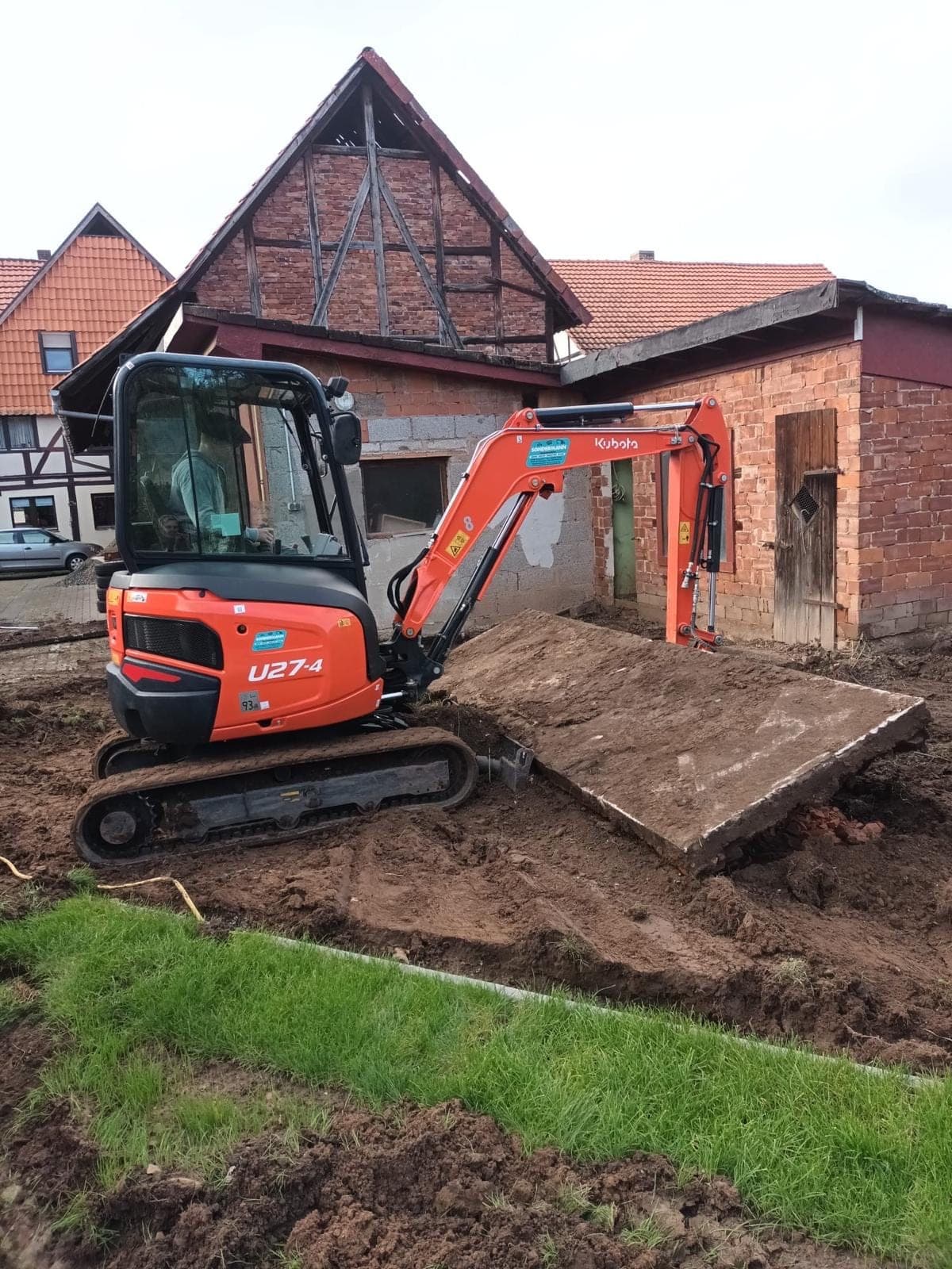 Kubota-Minibagger bei Erdarbeiten vor einem Fachwerkhaus
