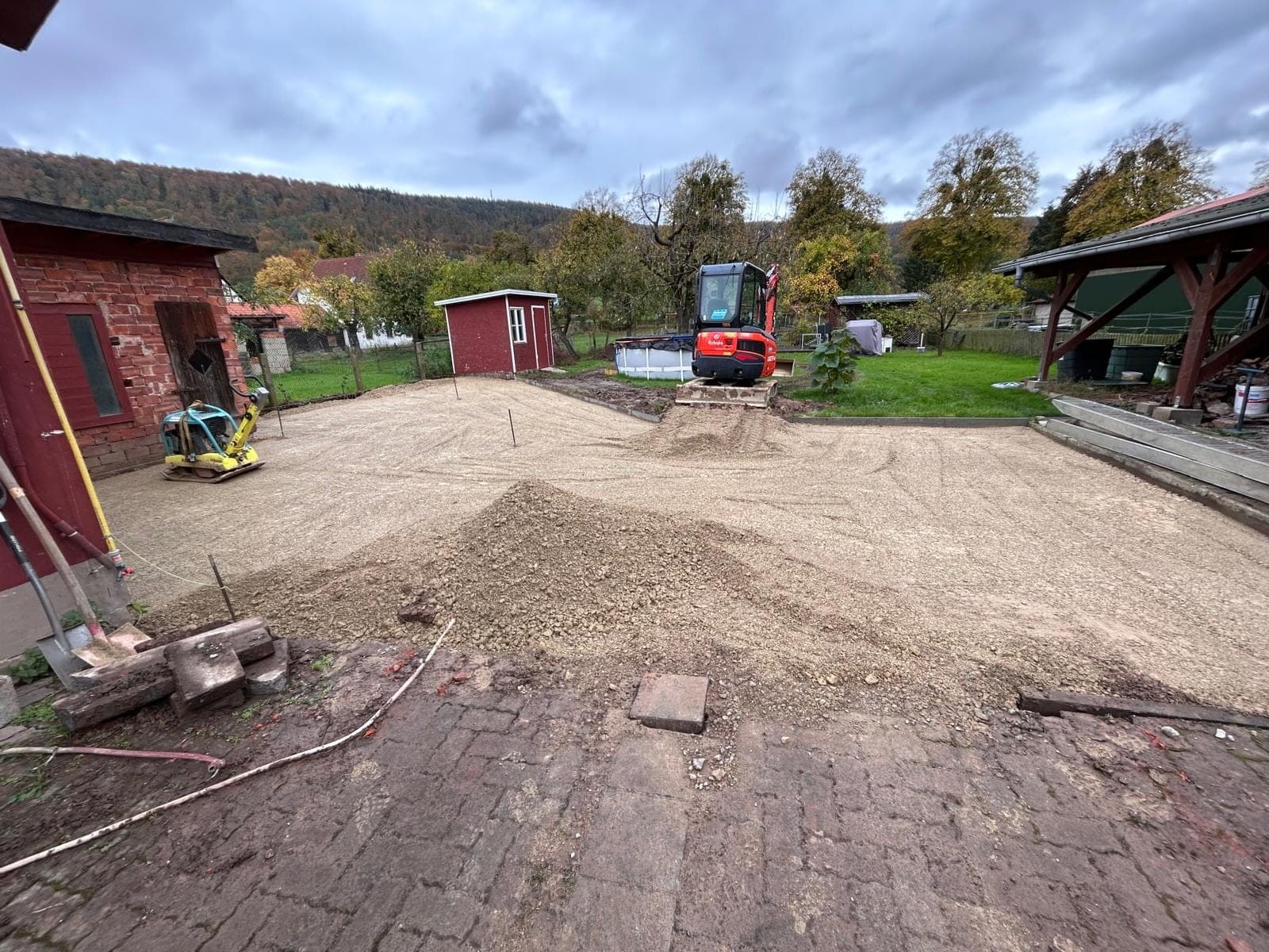 Frisch verdichtete Schotterfläche mit Minibagger im Hintergrund