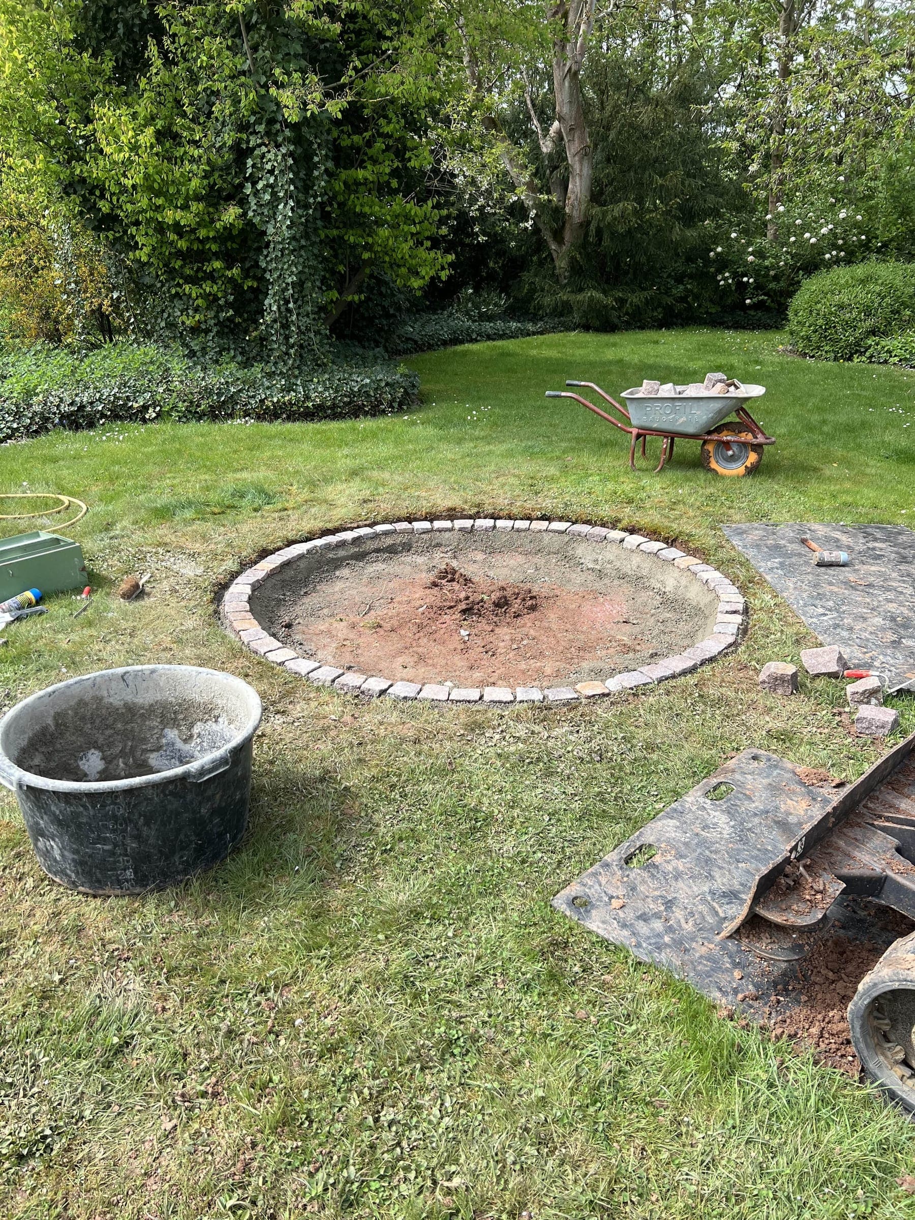 Arrangement aus Pflanzen und Trögen vor einem roten Gartenhaus