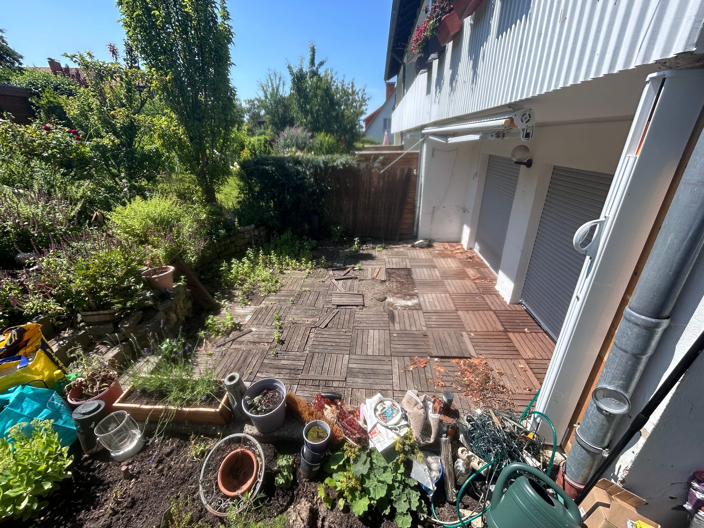 Vernachlässigte Holzterrasse mit verwitterten Lattenelementen vor einer Garage