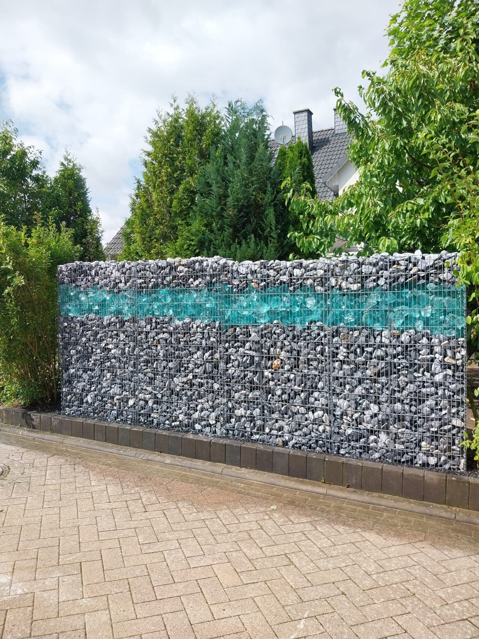 Gabionenwand als Sichtschutz an gepflasterter Auffahrt